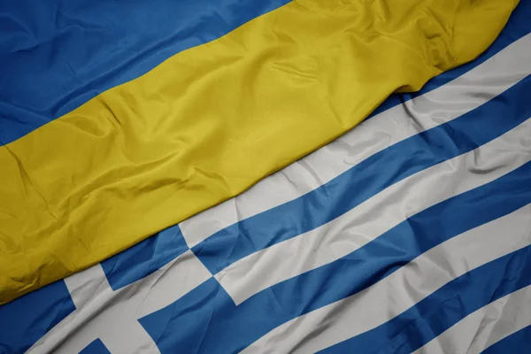 Ondeando colorida bandera de Grecia y bandera nacional de Ucrania . — Foto de Stock