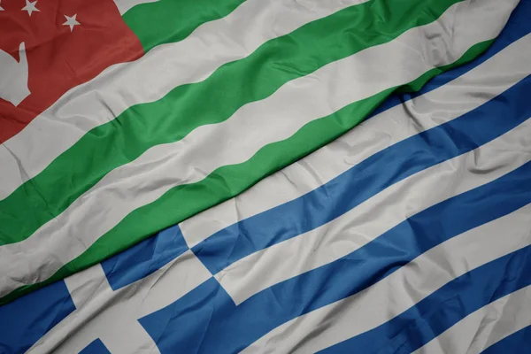 Ondeando colorida bandera de Grecia y bandera nacional de abjasia . — Foto de Stock