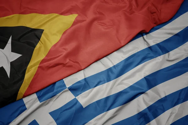 Acenando bandeira colorida de greece e bandeira nacional de timor leste . — Fotografia de Stock