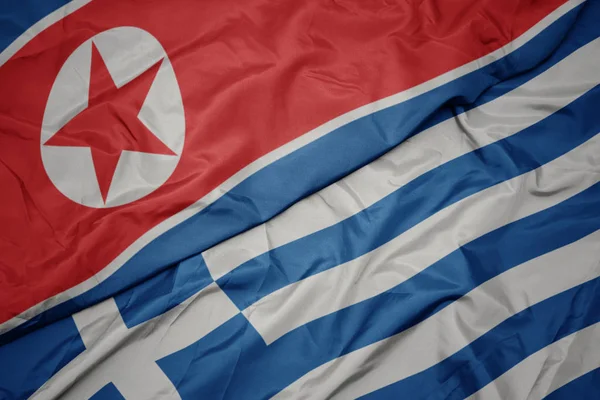 Zwaaiende kleurrijke vlag van Griekenland en de nationale vlag van Noord-Korea. — Stockfoto