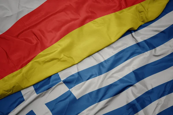 Acenando bandeira colorida da grécia e bandeira nacional da ossétia do sul . — Fotografia de Stock