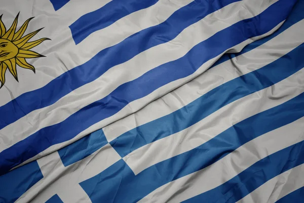 Ondeando colorida bandera de Grecia y bandera nacional de uruguay . —  Fotos de Stock