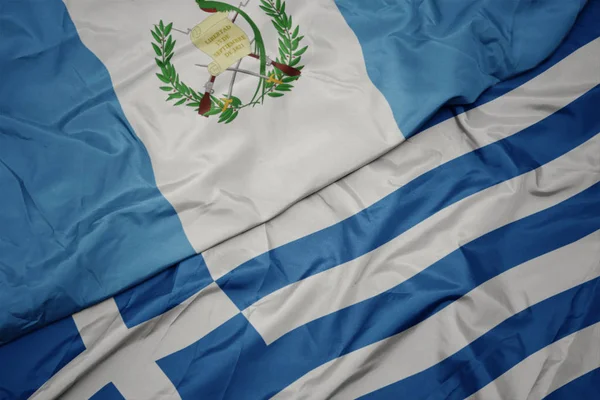 Mávající barevná vlajka Řecka a národní vlajka Guatemaly. — Stock fotografie