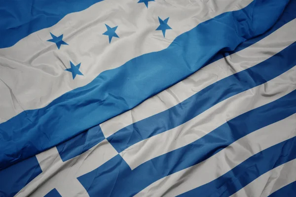 Schwenken bunte Flagge von Griechenland und Nationalflagge von Honduras. — Stockfoto