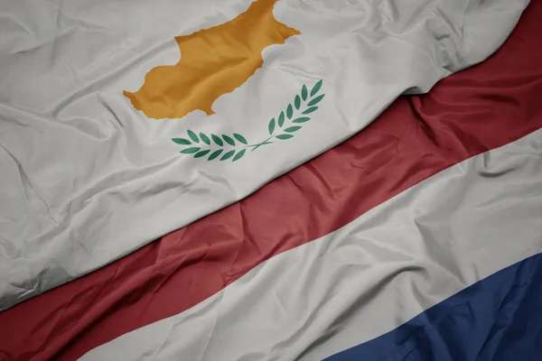 Mávající barvitá vlajka Nizozemska a národní vlajky Kypru. — Stock fotografie