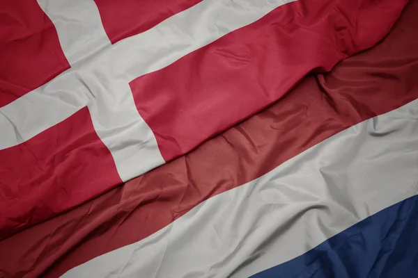 Vinka färgglada flagga av Nederländerna och nationella flaggan i Danmark. — Stockfoto