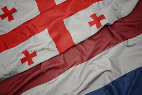 Vinka färgglada flagga av Nederländerna och nationella flaggan i Georgien. — Stockfoto