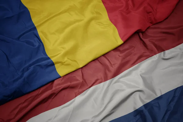 Sventolando bandiera colorata dei Paesi Bassi e bandiera nazionale della Romania . — Foto Stock