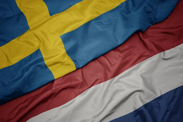 Waving colorful flag of netherlands and national flag of sweden. — Stock Photo, Image