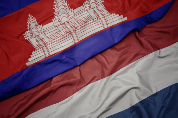 Ondeando colorida bandera de los Países Bajos y bandera nacional de Camboya . —  Fotos de Stock