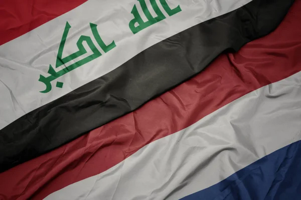 Sventolando bandiera colorata dei Paesi Bassi e bandiera nazionale dell'Iraq . — Foto Stock