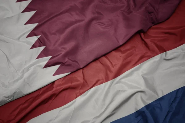 Schwenken bunte Flagge der Niederlande und Nationalflagge Katars. — Stockfoto