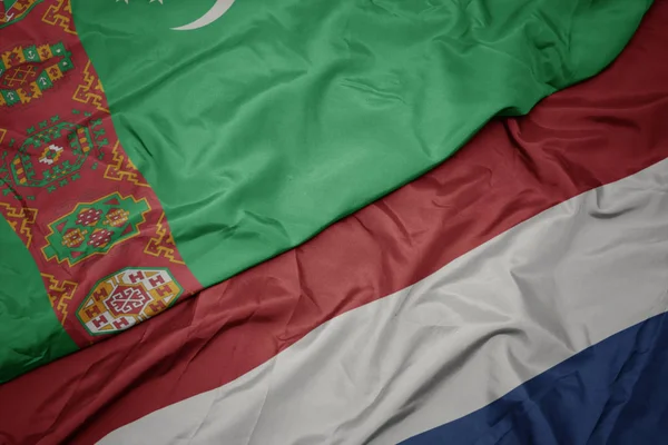 Mávající barvitá vlajka Nizozemska a národní vlajka Turkmenistánu. — Stock fotografie
