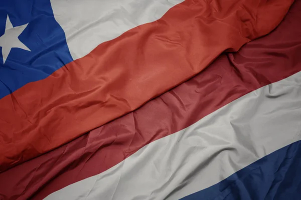 Ondeando colorida bandera de los Países Bajos y bandera nacional del chile . — Foto de Stock