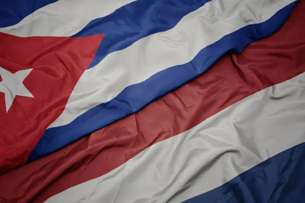 Ondeando colorida bandera de los Países Bajos y bandera nacional de Cuba . —  Fotos de Stock