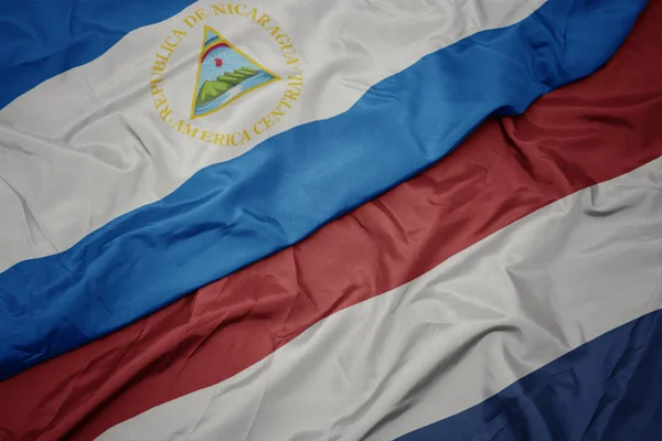 Acenando bandeira colorida de terras baixas e bandeira nacional de nicarágua . — Fotografia de Stock