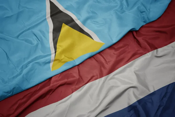 Agitant drapeau coloré des Pays-Bas et drapeau national de Sainte-Lucie . — Photo