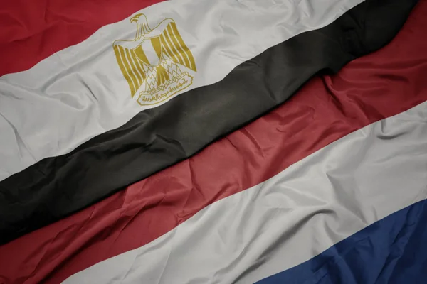 Zwaaiende kleurrijke vlag van Nederland en de nationale vlag van Egypte . — Stockfoto