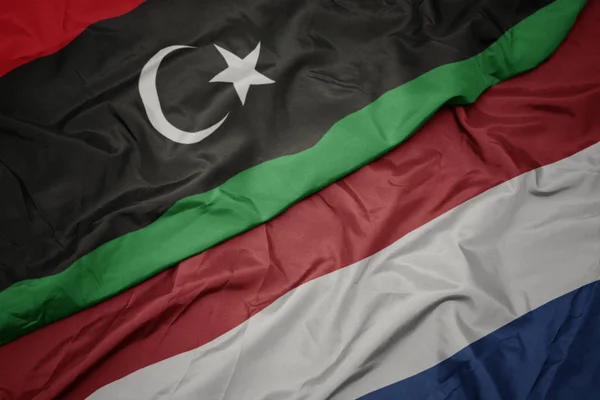 Waving colorful flag of netherlands and national flag of libya. — Stock Photo, Image