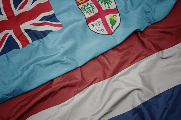 Waving colorful flag of netherlands and national flag of Fiji . — Stock Photo, Image