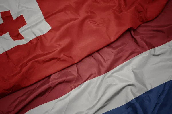 Waving colorful flag of netherlands and national flag of Tonga . — Stock Photo, Image