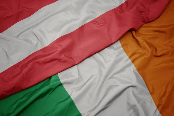 Agitant drapeau coloré de l'Irlande et drapeau national de l'Autriche . — Photo
