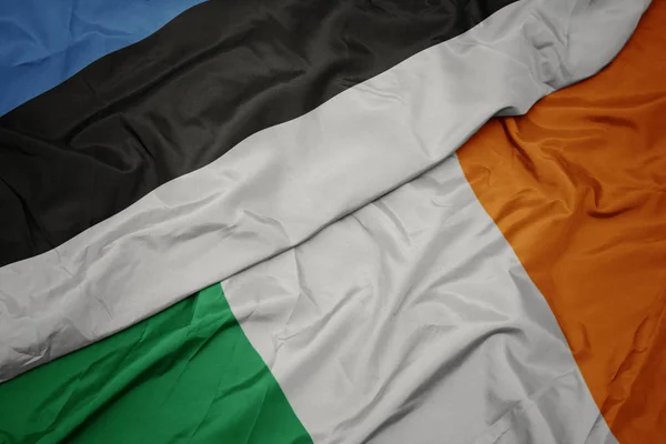 Ondeando colorida bandera de Irlanda y bandera nacional de Estonia . —  Fotos de Stock