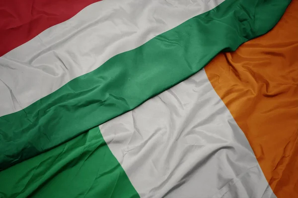 Agitant drapeau coloré de l'Irlande et drapeau national de la Hongrie . — Photo