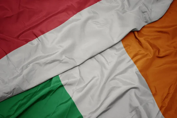 Mávající barevná vlajka Irska a národní vlajky Indonésie. — Stock fotografie