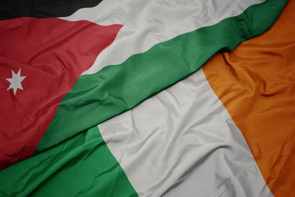 Acenando bandeira colorida da Irlanda e bandeira nacional da Jordânia . — Fotografia de Stock