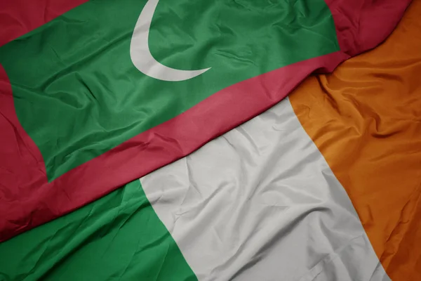 Waving colorful flag of ireland and national flag of maldives. — Stock Photo, Image