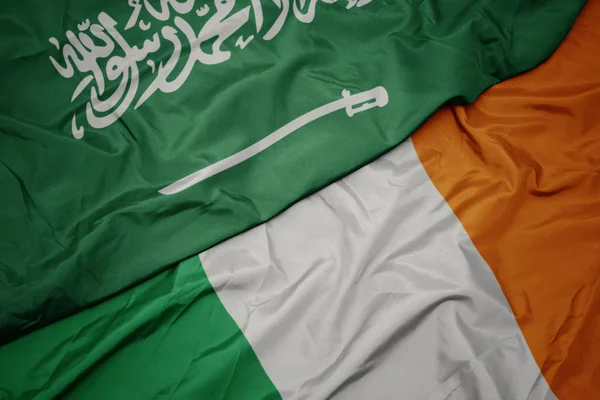 Acenando bandeira colorida da Irlanda e bandeira nacional da Arábia Saudita . — Fotografia de Stock