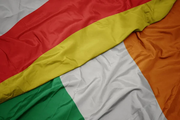 Ondeando colorida bandera de Irlanda y bandera nacional de Osetia del Sur . — Foto de Stock
