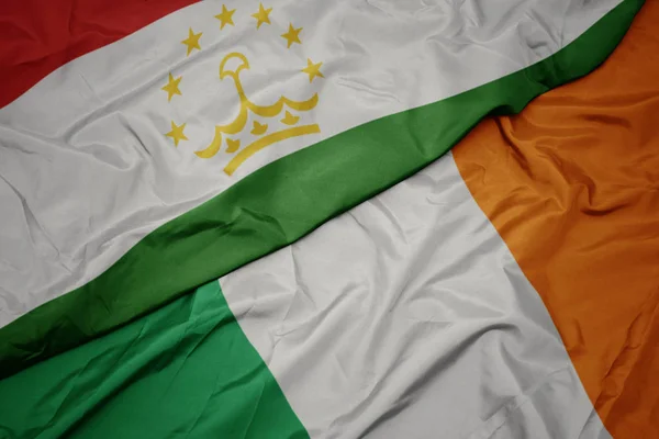 Sventolando bandiera colorata dell'Irlanda e bandiera nazionale del tajikistan . — Foto Stock