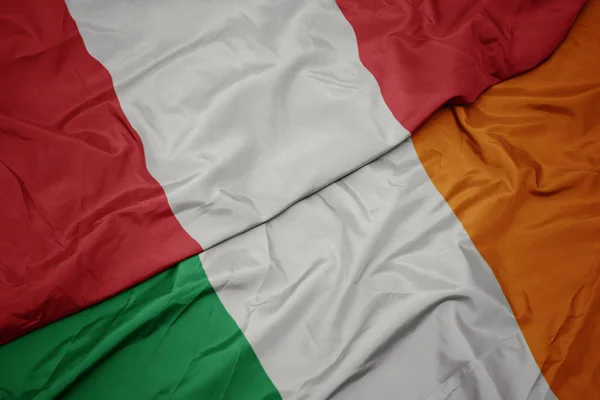 Agitant le drapeau coloré de l'Irlande et le drapeau national du Pérou . — Photo