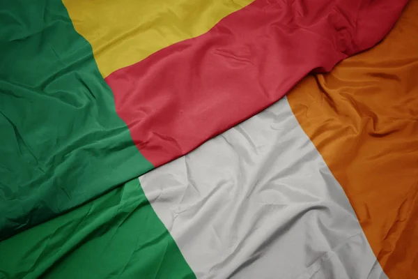 Stock image waving colorful flag of ireland and national flag of benin.