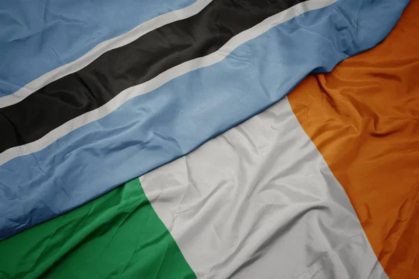 Agitant drapeau coloré de l'Irlande et drapeau national du Botswana . — Photo