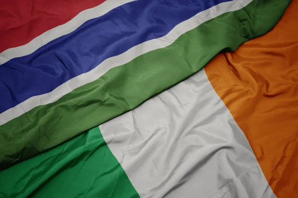 Schwenken bunte Flagge Irlands und Nationalflagge von Gambia. — Stockfoto