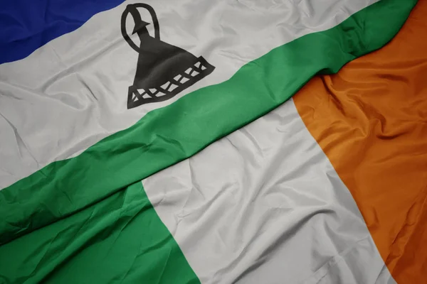 Agitant drapeau coloré de l'Irlande et drapeau national du Lesotho . — Photo