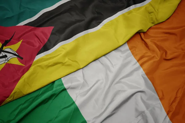 Mávající barevná vlajka Irska a národní vlajka Mosambiku. — Stock fotografie