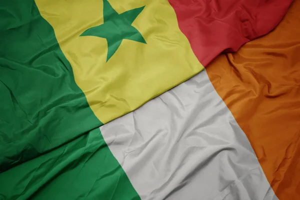 Waving colorful flag of ireland and national flag of senegal. — Stock Photo, Image