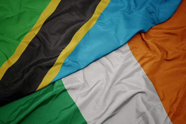 Agitant le drapeau coloré de l'Irlande et le drapeau national de la Tanzanie . — Photo