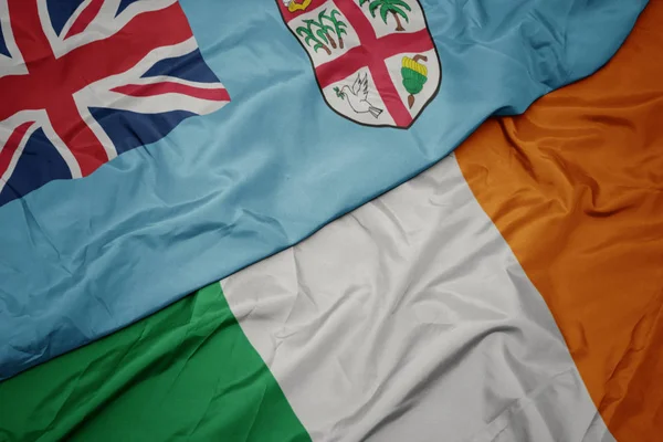 Waving colorful flag of ireland and national flag of Fiji . — Stock Photo, Image