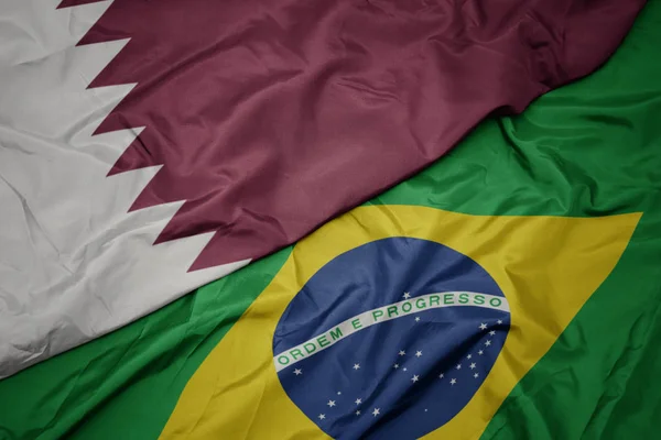 Falujące kolorowe flagi Brazylii i flagi narodowej Kataru. — Zdjęcie stockowe