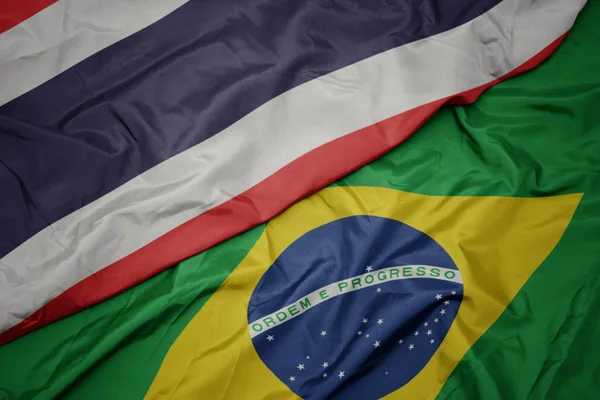 Ondeando colorida bandera de Brasil y bandera nacional de Tailandia . — Foto de Stock