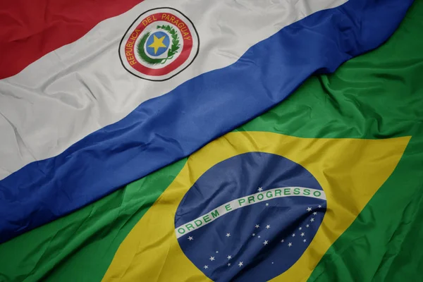 Agitant le drapeau coloré du Brésil et le drapeau national du paraguay . — Photo