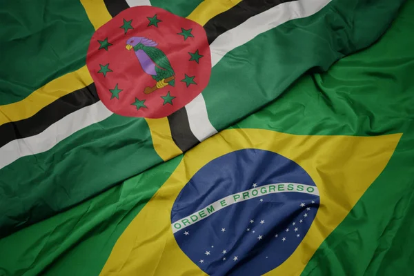 Ondeando colorida bandera de Brasil y bandera nacional de Dominica . — Foto de Stock