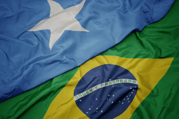 Ondeando colorida bandera de Brasil y bandera nacional de Somalia . — Foto de Stock