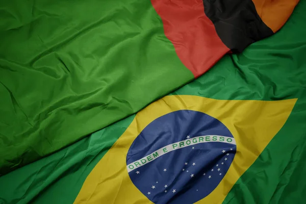 Ondeando colorida bandera de Brasil y bandera nacional de zambia . — Foto de Stock