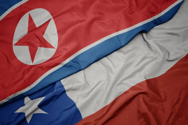 Ondeando colorida bandera de chile y bandera nacional de Corea del Norte . — Foto de Stock